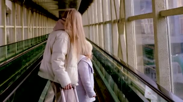 Mãe e filha sobem a escada rolante até o prédio da estação — Vídeo de Stock
