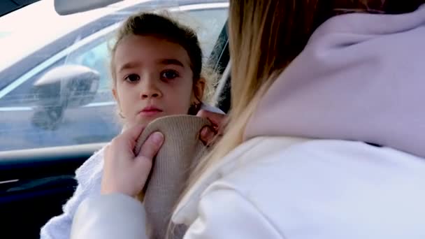 Mutter hilft Tochter, Hut aufzusetzen, bevor sie aus Auto steigt — Stockvideo
