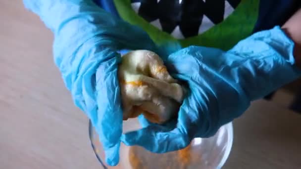 Дитячі руки в рукавичках замішують тісто — стокове відео