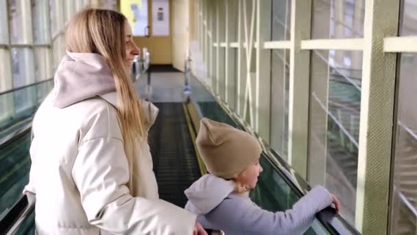 Mutter und Tochter steigen die Rolltreppe vom Bahnhofsgebäude zum Bahnsteig hinunter — Stockvideo