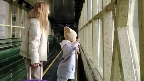 Mutter und Tochter steigen die Rolltreppe hinauf zum Bahnhofs- oder Flughafengebäude — Stockvideo