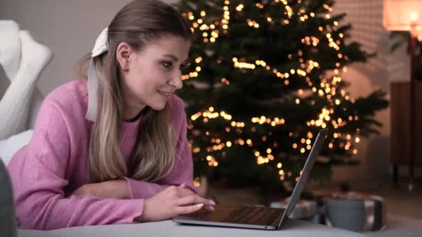 Молода красива біла жінка використовує ноутбук на дивані — стокове відео