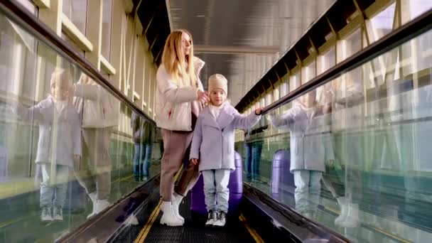 Maminka a dcera jdou po eskalátoru z nádražní budovy na nástupiště — Stock video