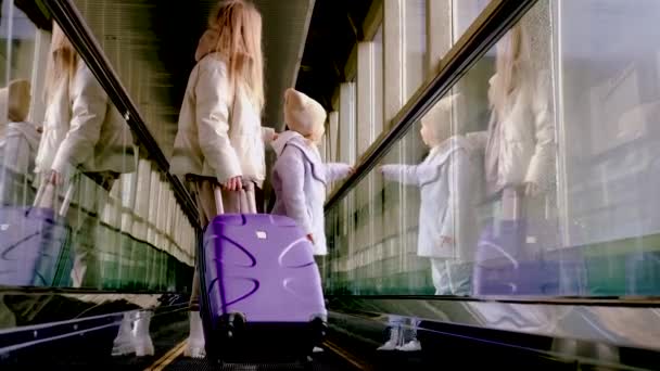 Mom and daughter go up the escalator to the building of the station — Stock Video