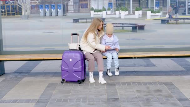 Otobüs durağında oturmuş otobüs beklerken anne kızının resim yapmasına yardım ediyor. — Stok video