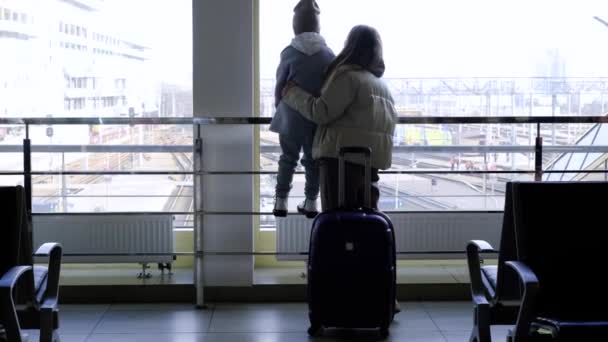 Мать и дочь стоят перед большим окном в здании вокзала — стоковое видео