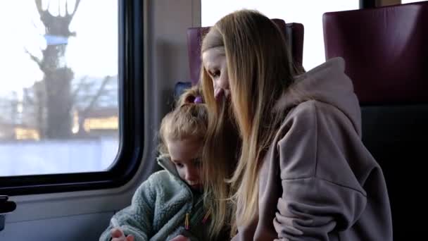 Moeder helpt haar dochter tekenen een beeld terwijl ze op de trein — Stockvideo