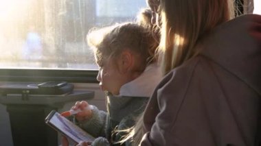 Annem, kızına trendeyken resim çizmesinde yardım ediyor.