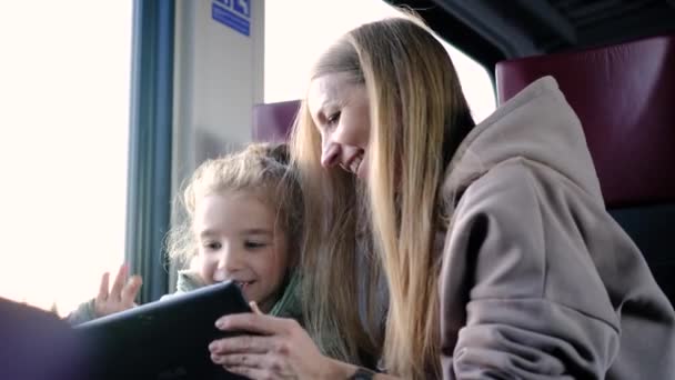 Madre e hija viajan en tren y juegan un juego en una tableta Minsk, Bielorrusia, 10 de diciembre de 2021 — Vídeo de stock