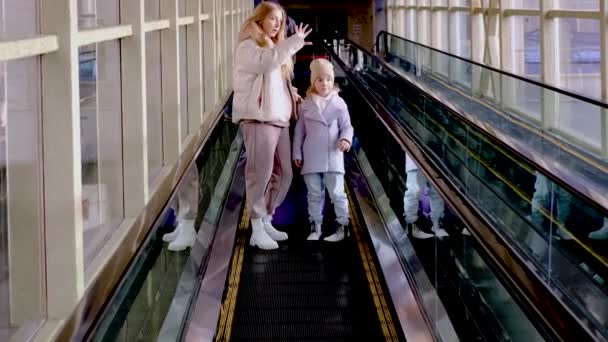 Mutter und Tochter steigen die Rolltreppe vom Bahnhofsgebäude zum Bahnsteig hinunter — Stockvideo