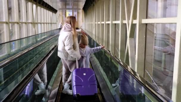 Mamá y su hija bajan por la escalera mecánica desde el edificio de la estación hasta la plataforma — Vídeo de stock