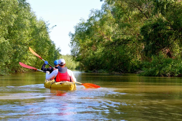 İki adam Tuna Nehri 'nde sarı bir kano sürüyor.