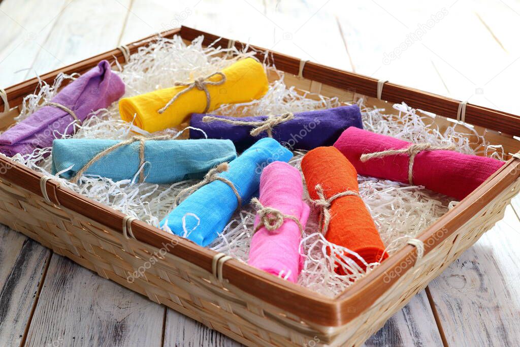 Rolls of multicolored clothes bound by a piece of rope on a tray