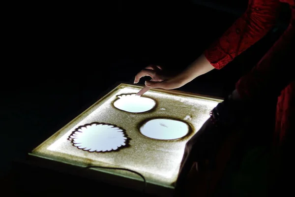Sand animation. Hands girls draw sand. Paint an illustration with sand on light table by finger. Art therapy