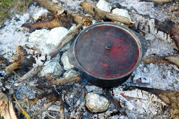 Folyodaki patatesler kömürle pişiriliyor. Auldron ateşte ısıtılır. Turist yemeği pişirmek.