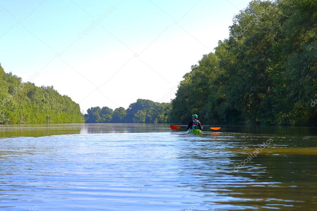 Man paddling in green kayak on a Danube river. Water tourism. Kayaking.