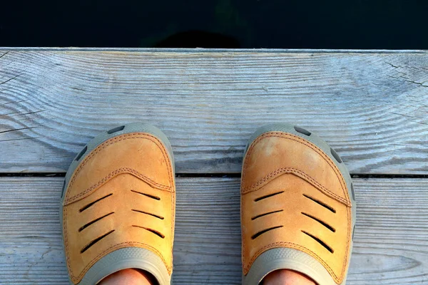 Feet Mustard Colored Slippers Crocs Stand Wooden Bridge Water Top — Stock Photo, Image