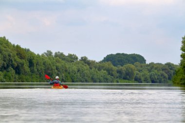 Kanocu adamın Tuna nehrindeki sarı kano görüntüsü. Yaz kayağı. Macera, seyahat, eylem, yaşam tarzı kavramı