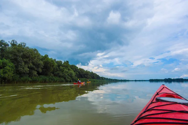 Sakin bir yaz gününde Tuna Nehri 'nde kano yaparken. Nehirde ve mavi gökyüzünde kırmızı kano pruvasına bakın. Su turizmi ve macera