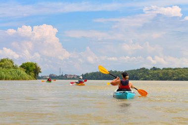 Bir grup arkadaş (insanlar) kanoyla seyahat eder. Yazın vahşi Tuna nehri ve biyosfer rezervlerinde birlikte kayak yapmak. Huzurlu bir nehir manzarası. Su turizmi kavramı