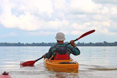 Kanocu adamın Tuna nehrindeki sarı kano görüntüsü. Yaz kayağı. Macera, seyahat, eylem, yaşam tarzı kavramı