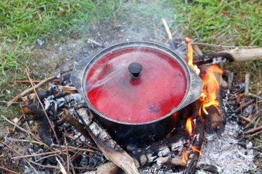 Turist bowlingi (kazan) şenlik ateşinde yemek, yürüyüş, açık hava aktiviteleri. Hazırlık yemeği yanıyor..