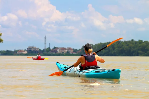 Kano yapıyorum. Mavi kanolu bir kadın. Sakin bir yaz günü, Tuna Nehri kıyısında yeşil ağaçlarla kürek çeken bir kız.