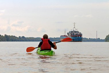 Yazın Tuna nehrinde yeşil kano süren bir adam. Yaz kayağı. Macera, seyahat, eylem, yaşam tarzı kavramı