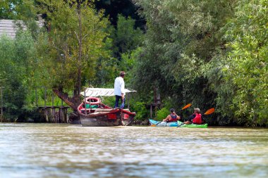 Ukrayna 'nın Tuna Nehri kıyısındaki Vilkovo şehrindeki kanal caddesinde bir adam motorlu teknede turist olarak duruyor.