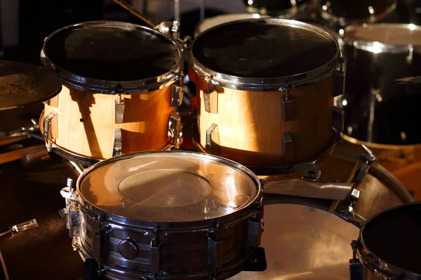 Drum set illuminated by the rays of the setting sun in a music studio. Closeup.