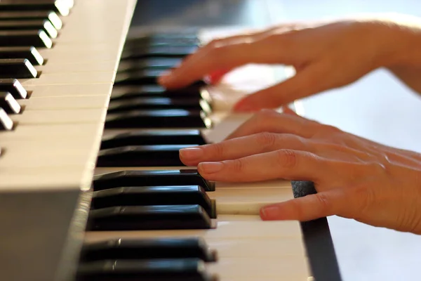 Woman\'s hands on the keyboard of the piano (electronic organ) closeup. Hands musician playing the piano. Hands pianist playing music on the piano. Musical education concept.