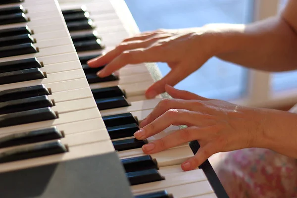 Woman\'s hands on the keyboard of the piano (electronic organ) closeup. Hands musician playing the piano. Hands pianist playing music on the piano. Musical education concept.