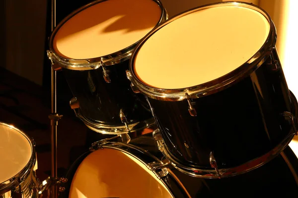 Drum set illuminated by the rays of the setting sun in a music studio. Closeup.