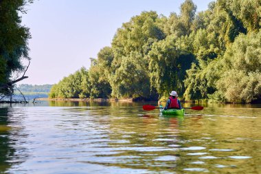 Zarif hasır şapkalı kanocu kadın Tuna Nehri 'nde yeşil kano sürüyor. Yaz Suyu Sporu