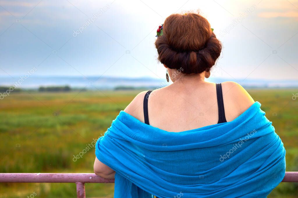 Woman in a blue scarf on her shoulder. Back view