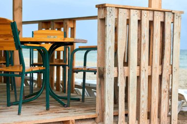 Fragment of a bar made of pallet on a sandy beach near the sea. Chaise lounge near the bar on a sandy, deserted sea beach