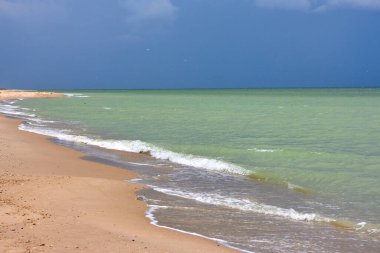 Sandy beach shore and cloudy stormy sky over the sea