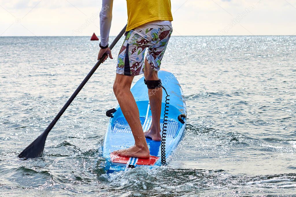 Man is training on SUP board on sea. Stand up paddle boarding - awesome active recreation in nature.
