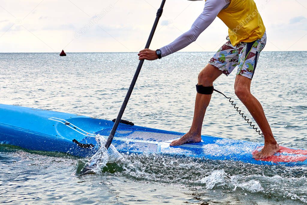 Man is training on SUP board on sea. Stand up paddle boarding - awesome active recreation in nature.