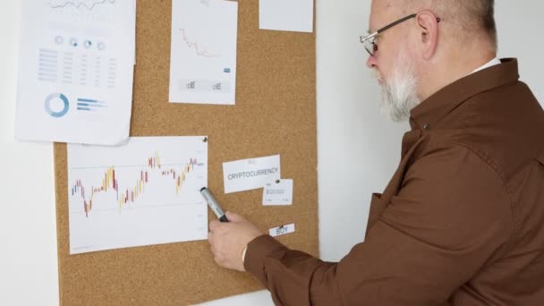 Elderly Man Examines Charts Stock Market Board — Stock Video
