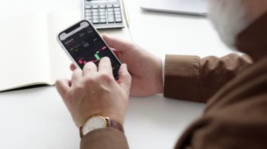 Yaşlı bir adam telefonuyla borsayı keşfediyor.
