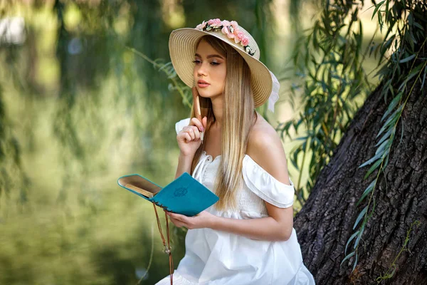 Beyaz elbiseli güzel bayan doğayla ilgili bazı notlar alıyor.
