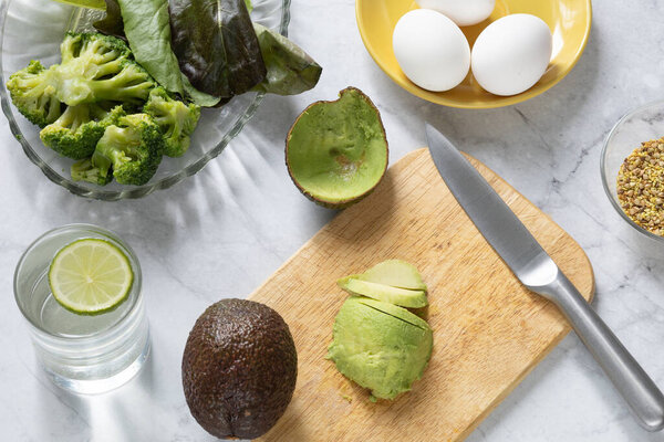 Cooking breakfast with eggs, avocado and broccoli, top view. Healthy eating concept.