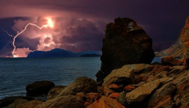 Karadeniz kıyısında ve Koktebel yakınlarındaki Karadeniz 'in kayalık kıyılarında gökyüzünde şimşekler çakıyor. Karamsar gökyüzünde bulutlar var. Yıldırım suya yansıyor. Doğanın olağanüstü gücü ve enerjisi, elementler. Fantezi tarzı 