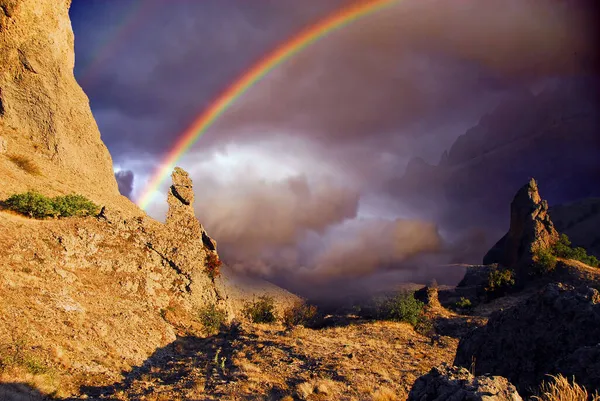 Karadeniz 'in kayalık kıyılarında gökkuşağı, Koktebel yakınlarında, Karadağ sıradağları. Dağların tepesinde, karamsar bulutların arasında bir gökkuşağı görünüyor.