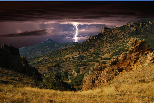 Karadağ 'ın kayalarının üzerinde şimşek çakıyor. Karadeniz kıyısı, Doğu Kırım. Dağlarda yıldırımlar ve parıltılarla çarpıcı bir fırtına manzarası