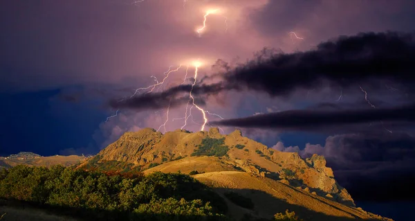 Karadağ 'ın kayalarının üzerinde şimşek çakıyor. Karadeniz kıyısı, Doğu Kırım, dağlarda çarpıcı bir fırtına manzarası, yıldırımlar ve parıltılarla