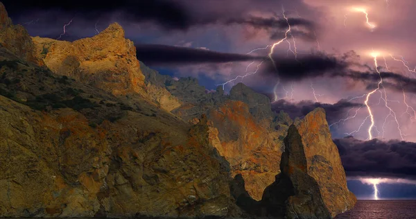 Karadağ 'ın kayalarının üzerinde şimşek çakıyor. Karadeniz kıyısı, Doğu Kırım, dağlarda çarpıcı bir fırtına manzarası, yıldırımlar ve parıltılarla