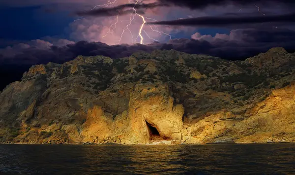 Karadağ 'ın kayalarının üzerinde şimşek çakıyor. Karadeniz kıyısı, Doğu Kırım, dağlarda çarpıcı bir fırtına manzarası, yıldırımlar ve parıltılarla