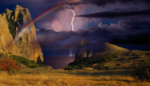 Karadeniz 'in kayalık kıyılarında gökkuşağı ve şimşek, Doğu Kırım' daki Koktebel yakınlarındaki Karadağ dağ sırasının kayalık uçurumlarındaki fırtınanın çarpıcı görüntüsü.. 